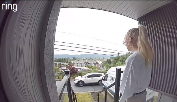 Woman standing at the front door while husband pulls up in a white car